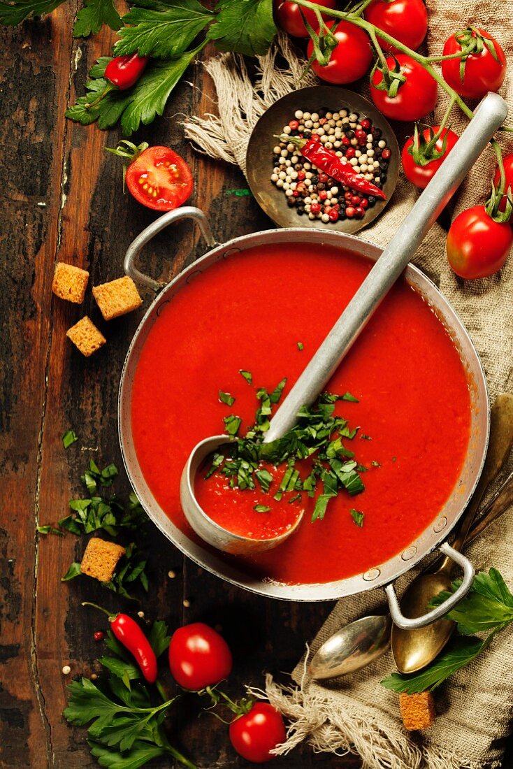 Hausgemachte Tomatencremesuppe im Topf auf rustikalem Holztisch (Aufsicht)