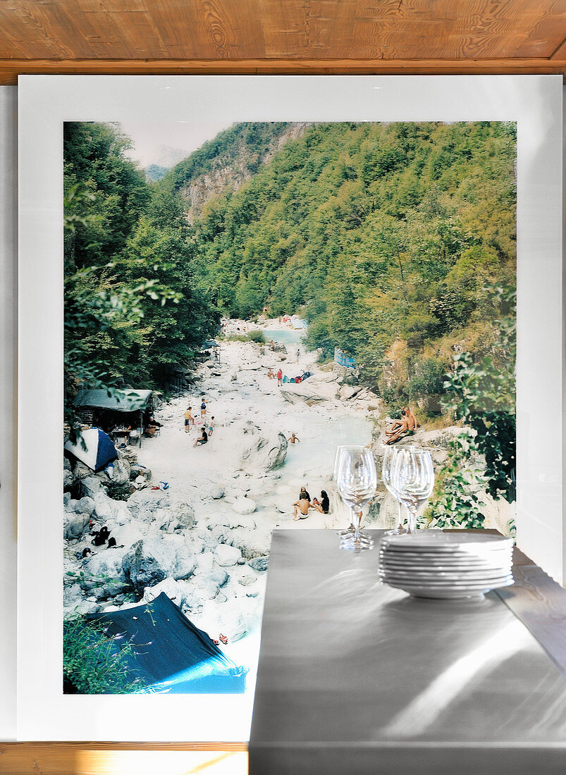 Stacked plates and glasses on counter in front of large landscape photo