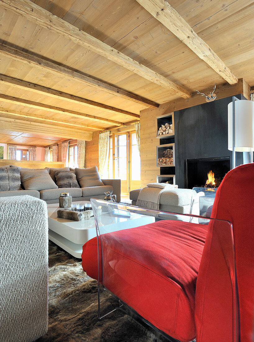 Moderne Möbel im Wohnzimmer mit Holzdecke und offenem Kamin