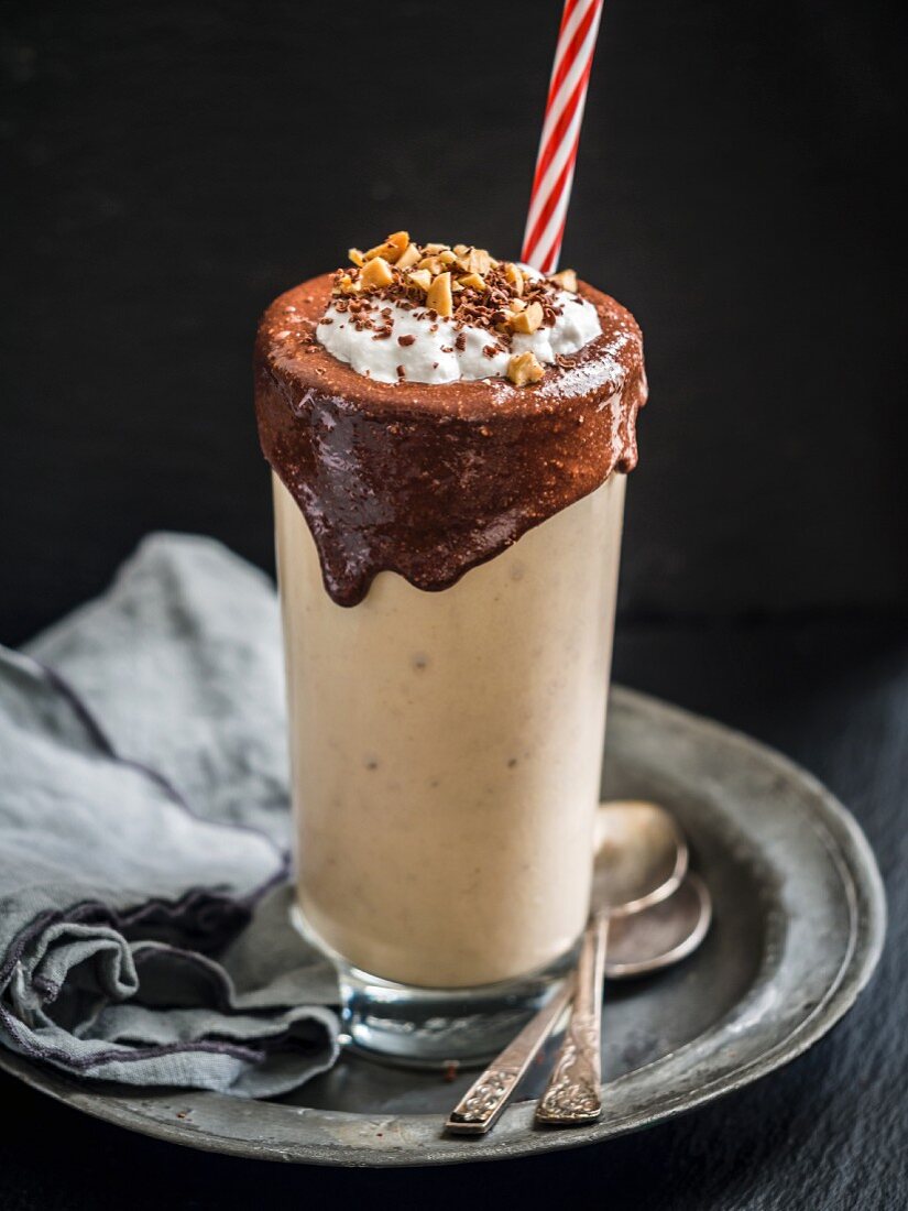 Veganer Erdnussbutter-Bananen Smoothie im Glas mit Schokoladen-Topping