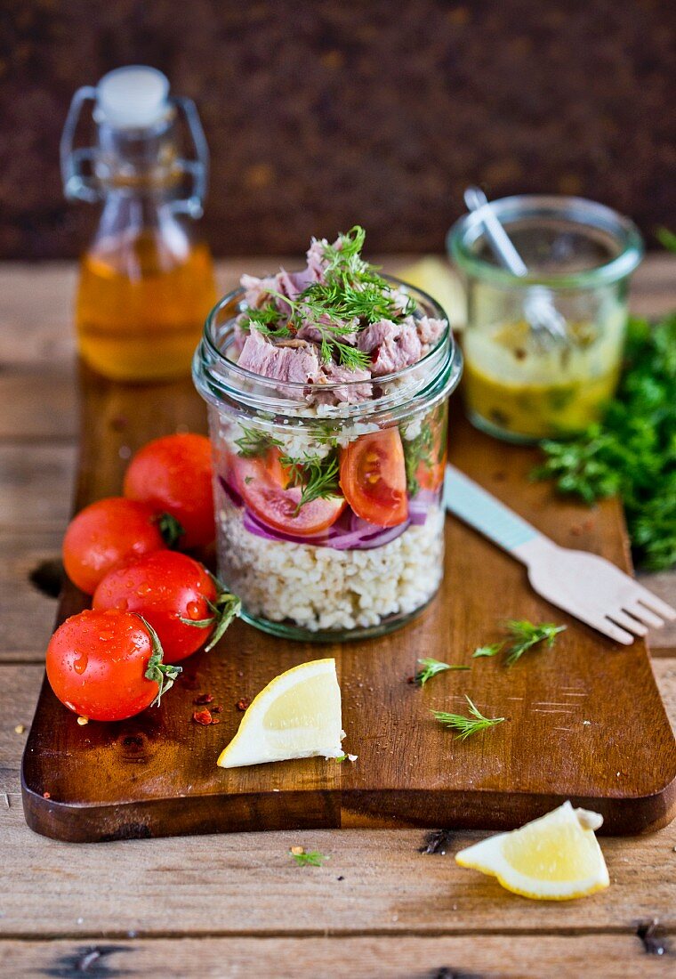 Bulgur salad with tuna, red onion and tomatoes in a glass jar