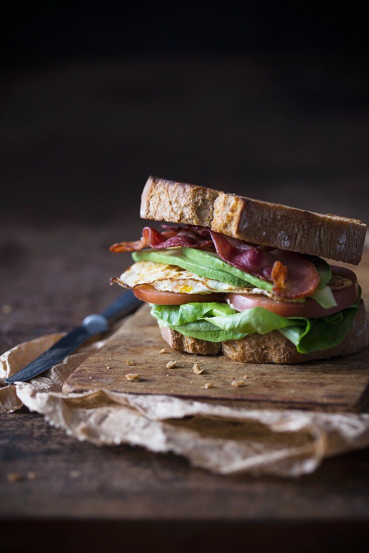 Sandwich with fried egg, bacon, avokado and tomato