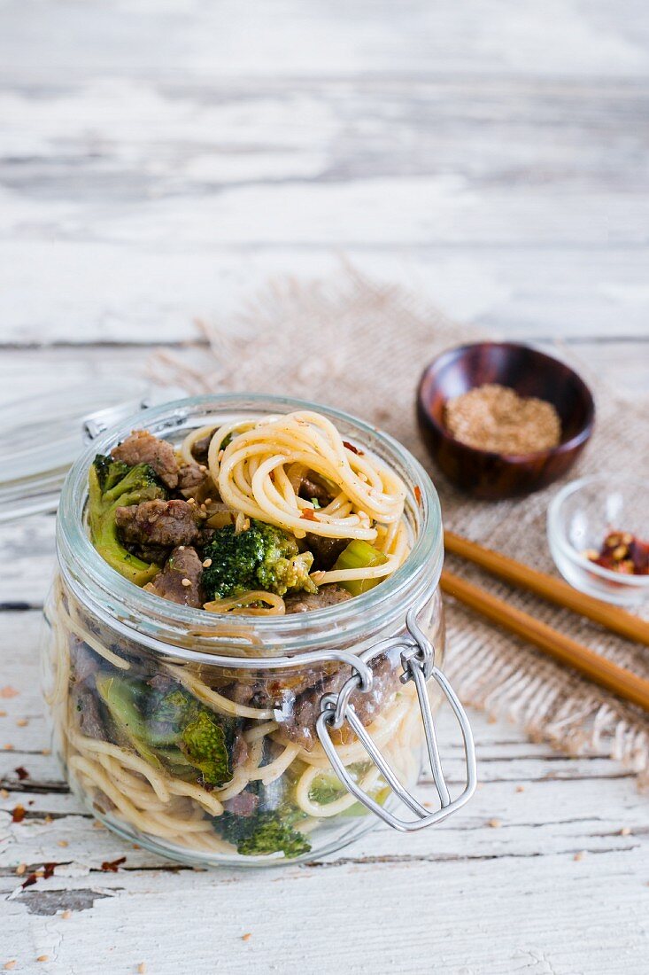 Noodles with beef and broccoli in a glass jar