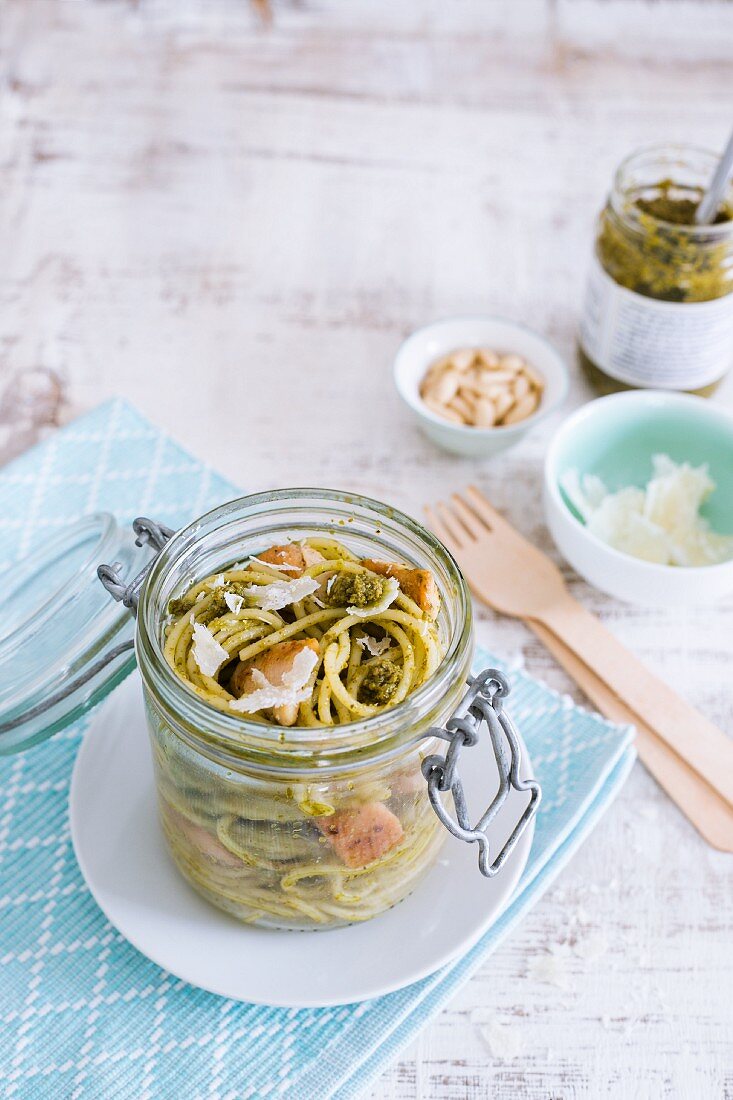 Spaghetti with chicken and pesto in a glass jar
