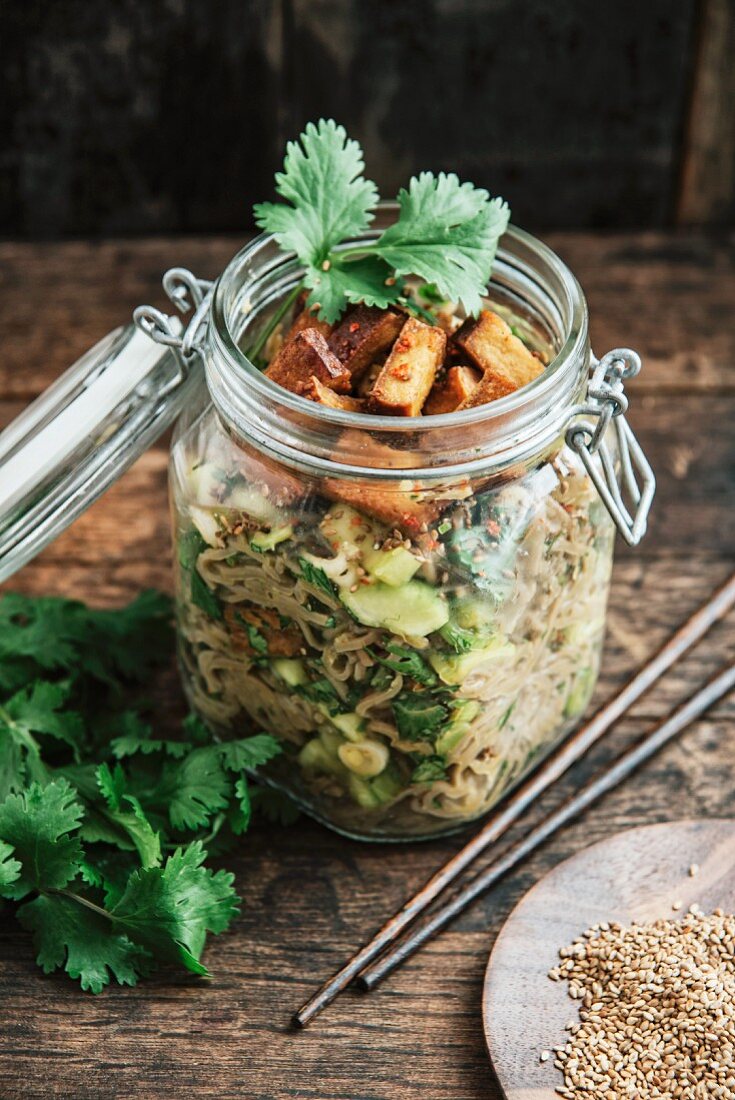 Veganer Otsu-Salat im Glas mit Buchweizennudeln, Gurken, Koriander, Tofu, Frühlingszwiebeln, Chili, Sesamöl und Ingwer (Japan)