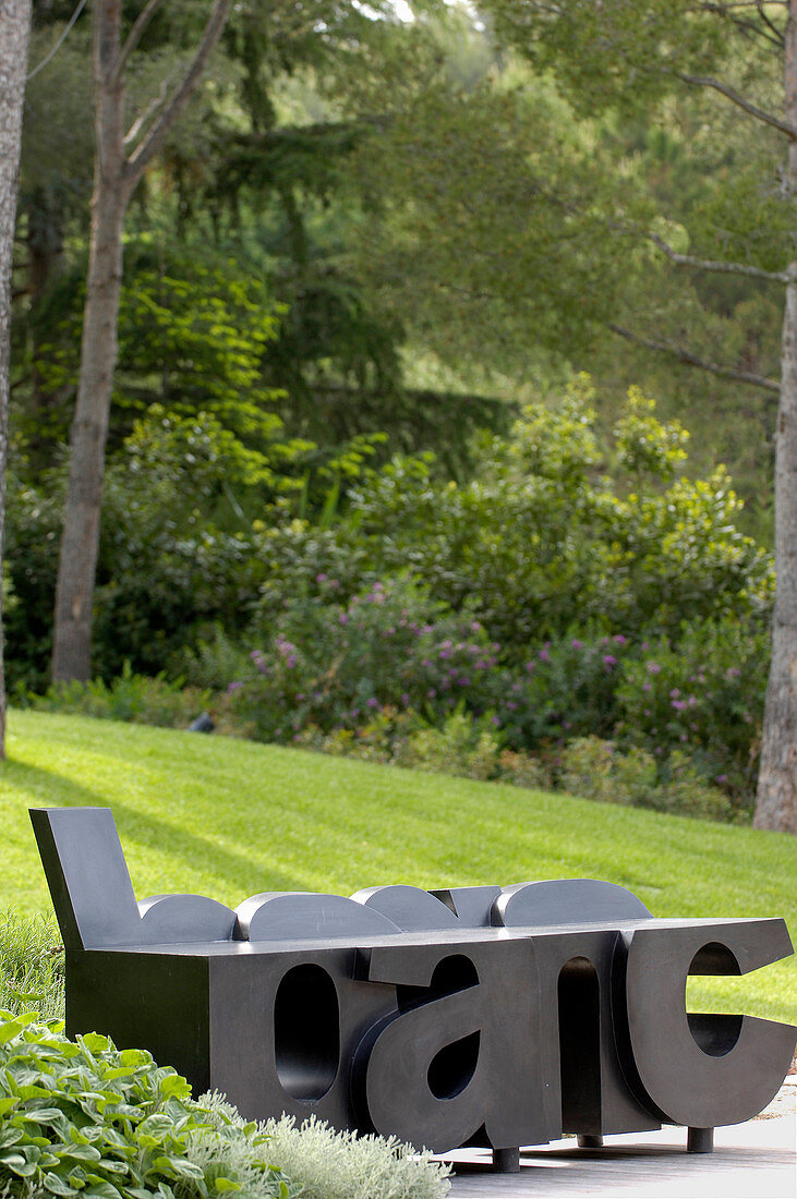 Artistic bench made from large black letters in garden