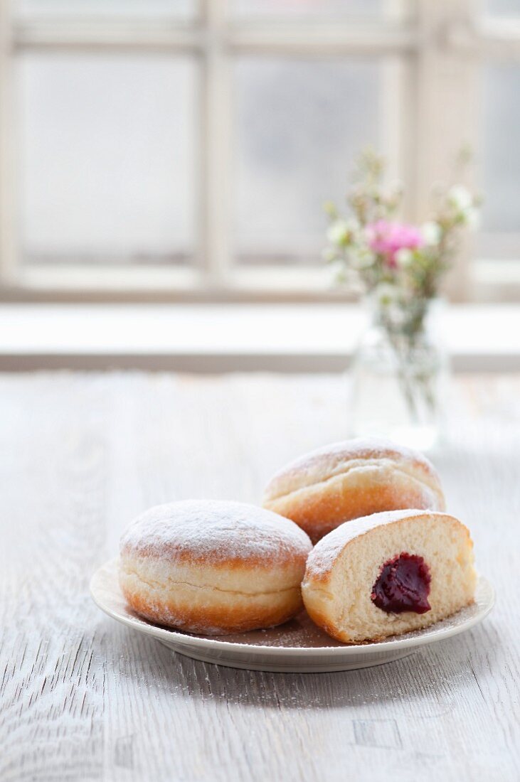 Jam doughnuts on a plate next to a window