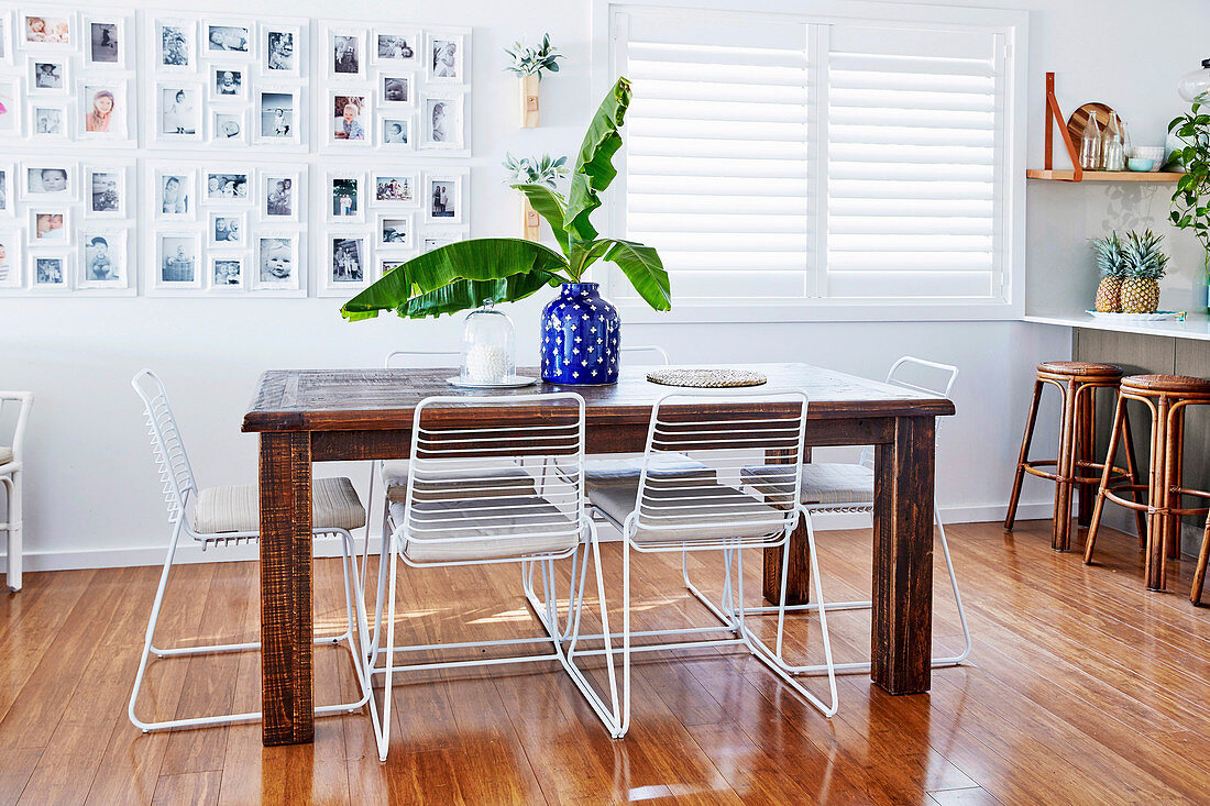 Rustic wooden table with white metal chairs, photo gallery next to the window in the open kitchen