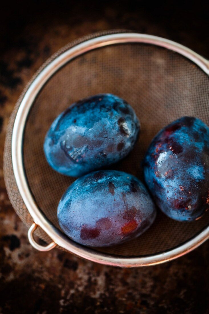 Three plums in a colander