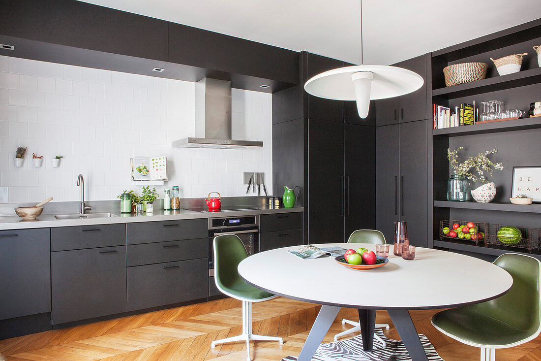 Round dining table and retro chairs on zebra-skin rug in grey fitted kitchen