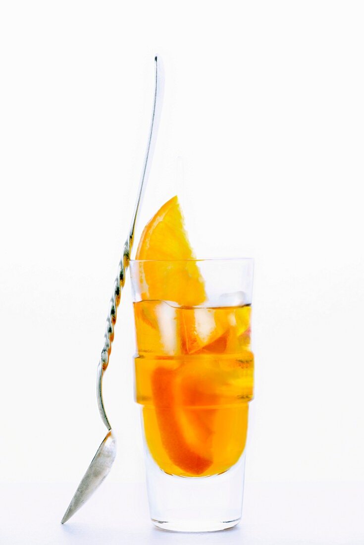 A glass of Amaro Nonino, an Italian herbal liqueur, with ice cubes and orange slices