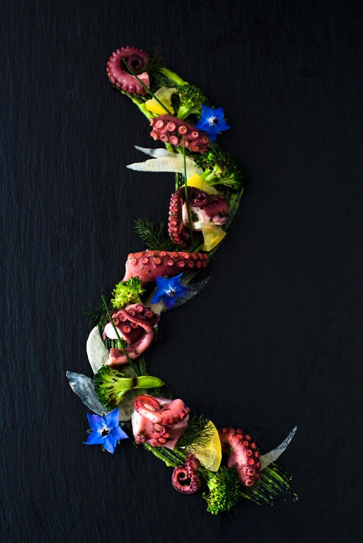 Vorspeise mit eingelegtem Oktopus, Zitronen und gegrillten Brokkoliröschen auf Salsa Verde mit Borretschblüten