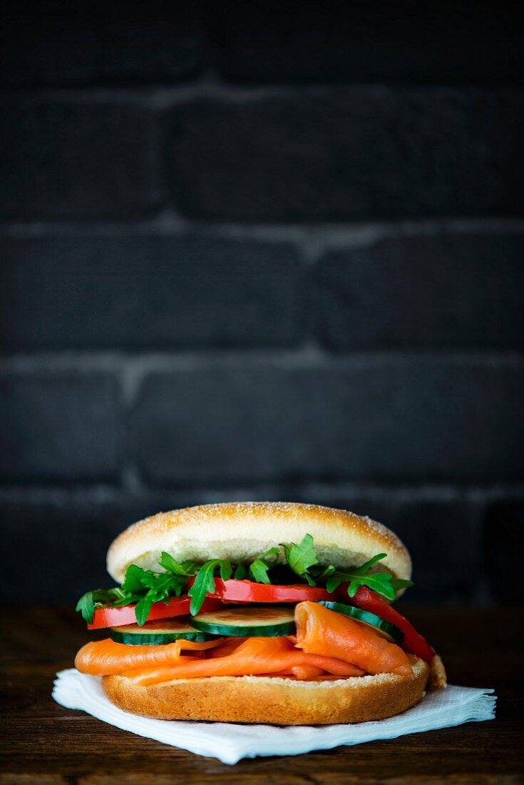A bagel with smoked salmon, cucumber, tomato and rocket