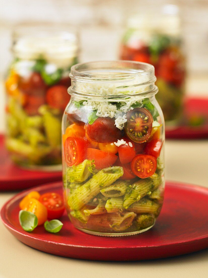 Pasta salad with pesto and cherry tomatoes in a glass jar