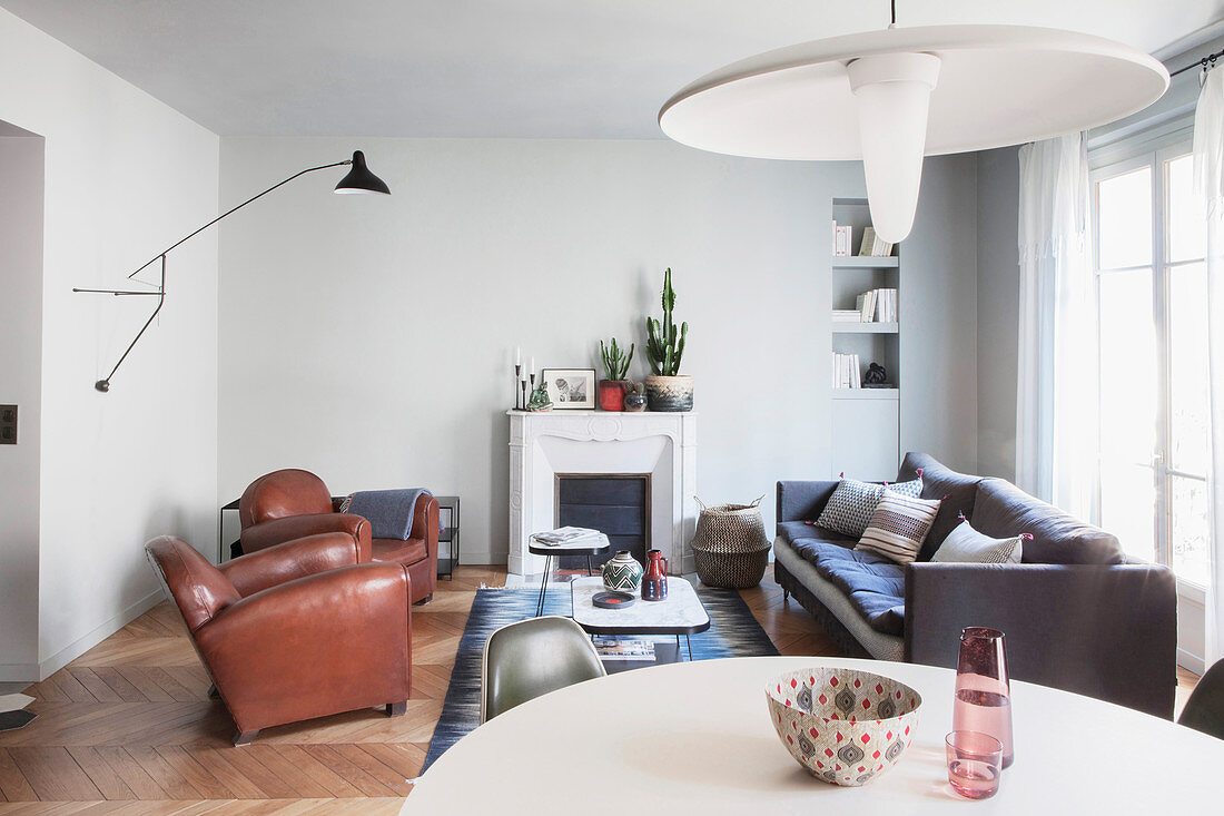 View across dining table into living area with leather armchairs and fireplace