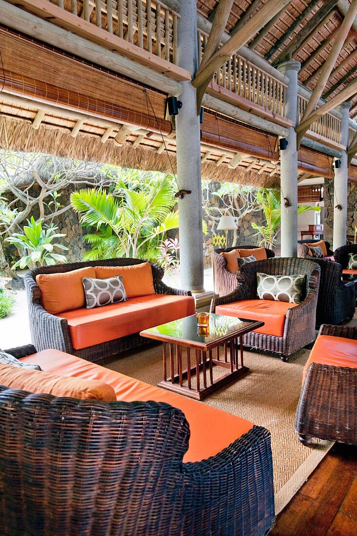 Wicker chairs with orange seat cushions in exotic lounge
