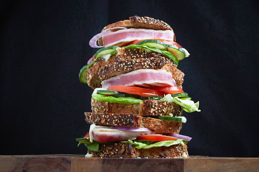 Ein Stapel Thunfischsteak-Sandwiches mit Salat, Tomaten, Gurken und Artisan Bread