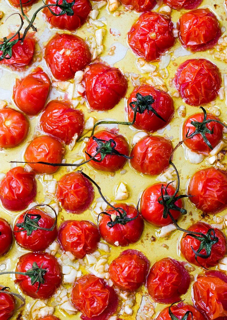 Ofengebratene Cocktailtomaten mit Knoblauch auf Ofenblech (Aufsicht)