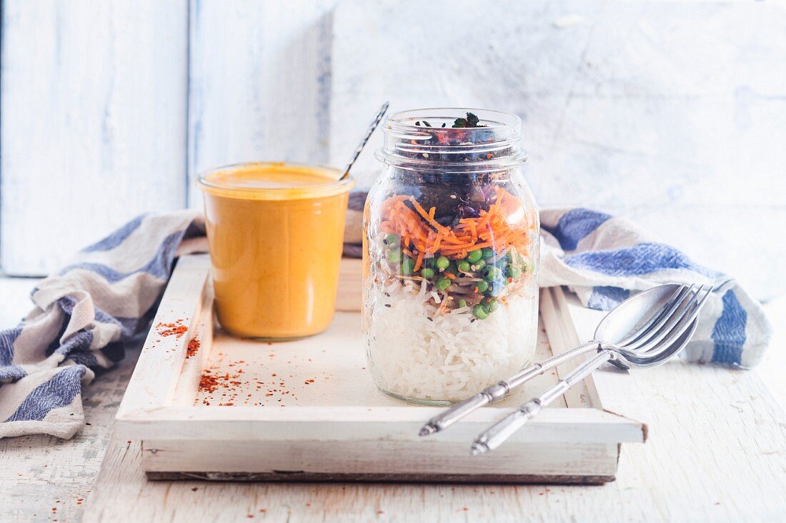 Veganer Reissalat im Glas mit Mungobohnenkeimlingen, Erbsen, Karotten, Rosenkohl mit Thai-Erdnuss-Chili-Sauce