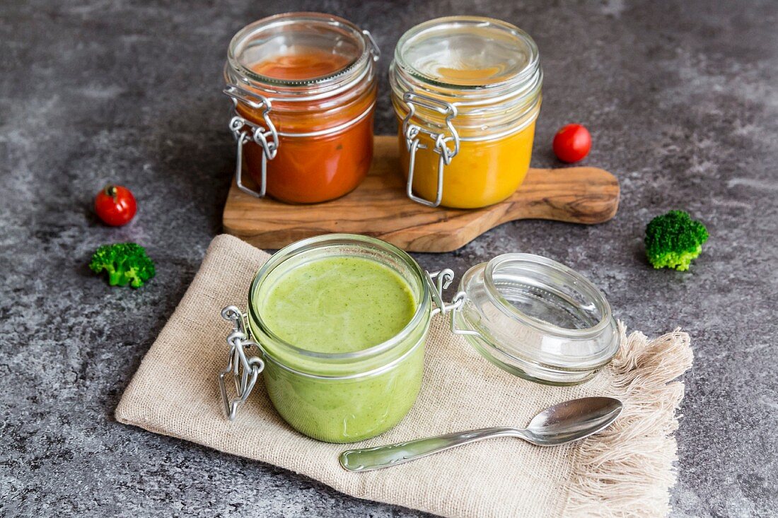 Various colourful soups in glass jars (broccoli soup, tomato soup, pumpkin soup))