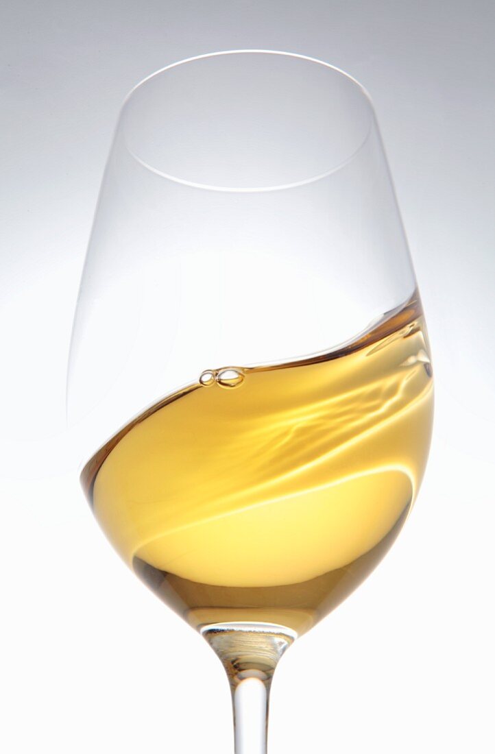 A glass of white wine being swirled