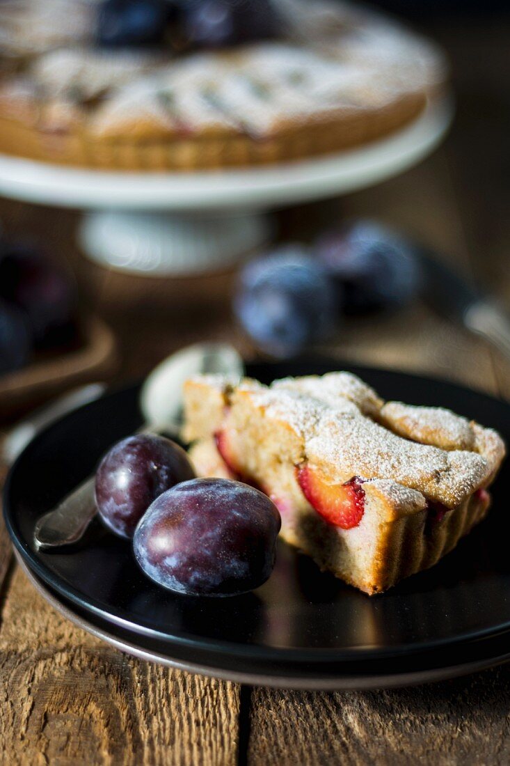 A slice of wholegrain plum cake with icing sugar