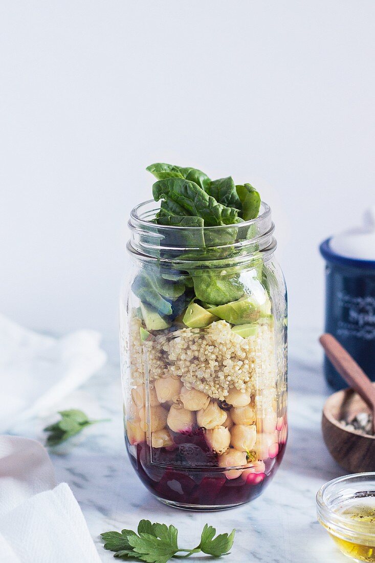 Layered salad with quinoa and vegetables in a glass jar