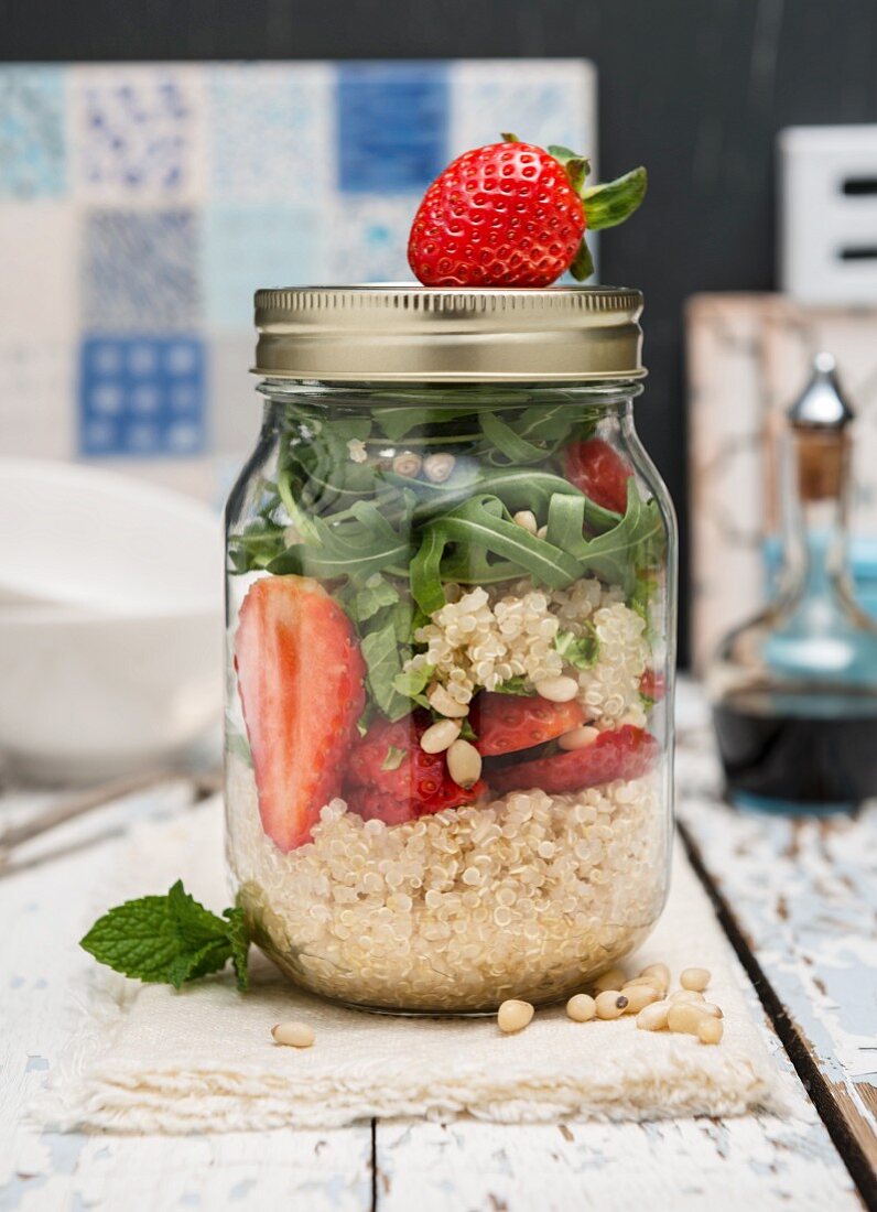 Vegan quinoa salad with strawberries and rocket in a jar