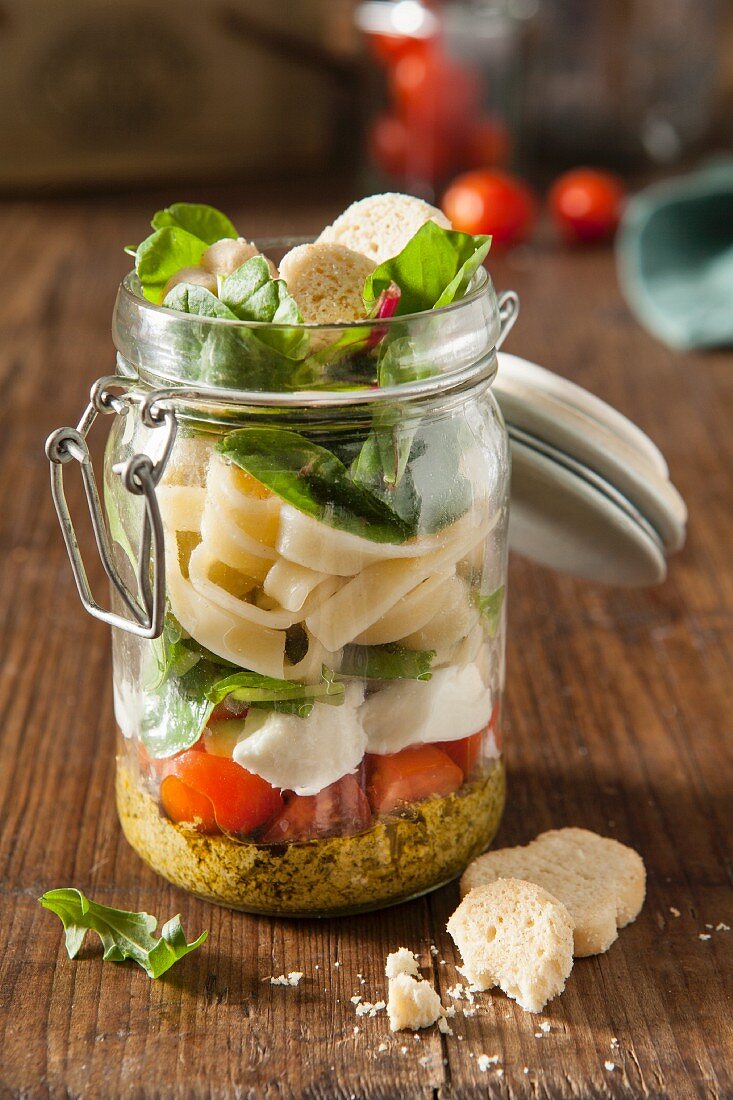 Italian pesto pasta vegetarian lunch jar in a rustic setting
