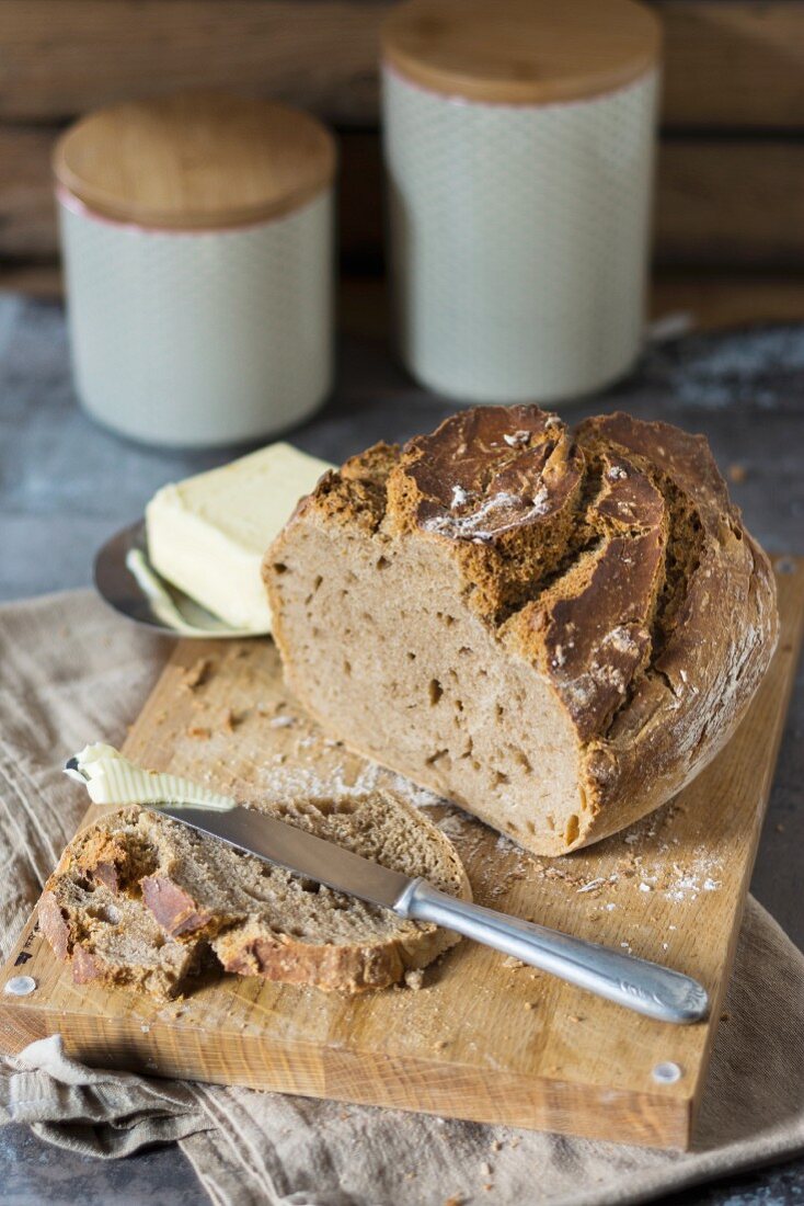 Homemade beer bread baked in a clay pot with butter on a wooden board