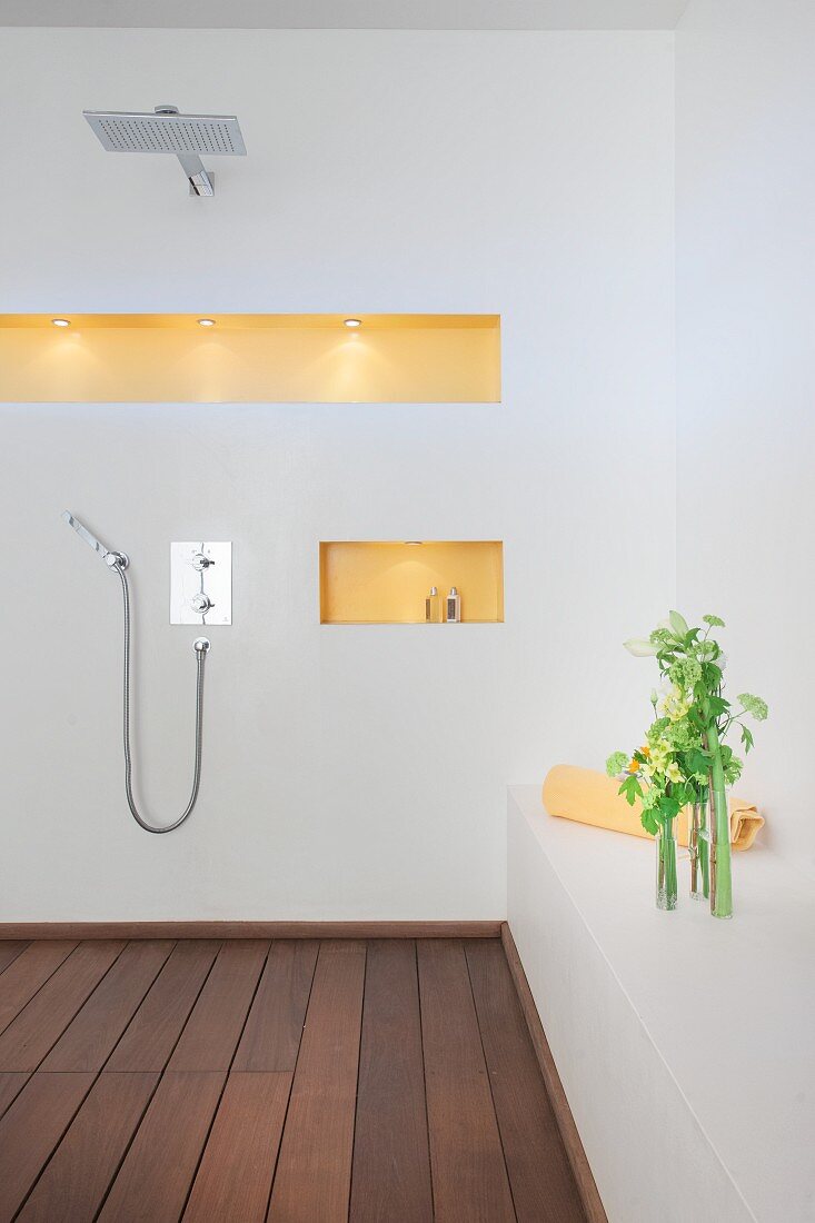 Open shower area, wooden floor and niches in wall of bathroom