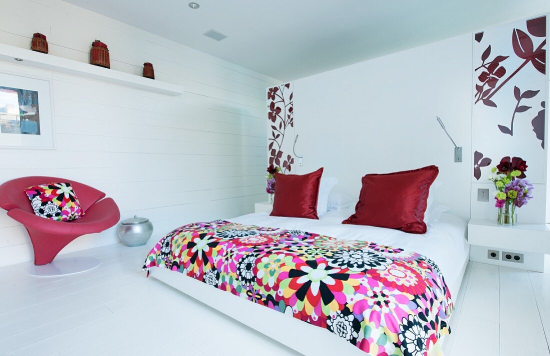 Red accents and floral patterns in white bedroom
