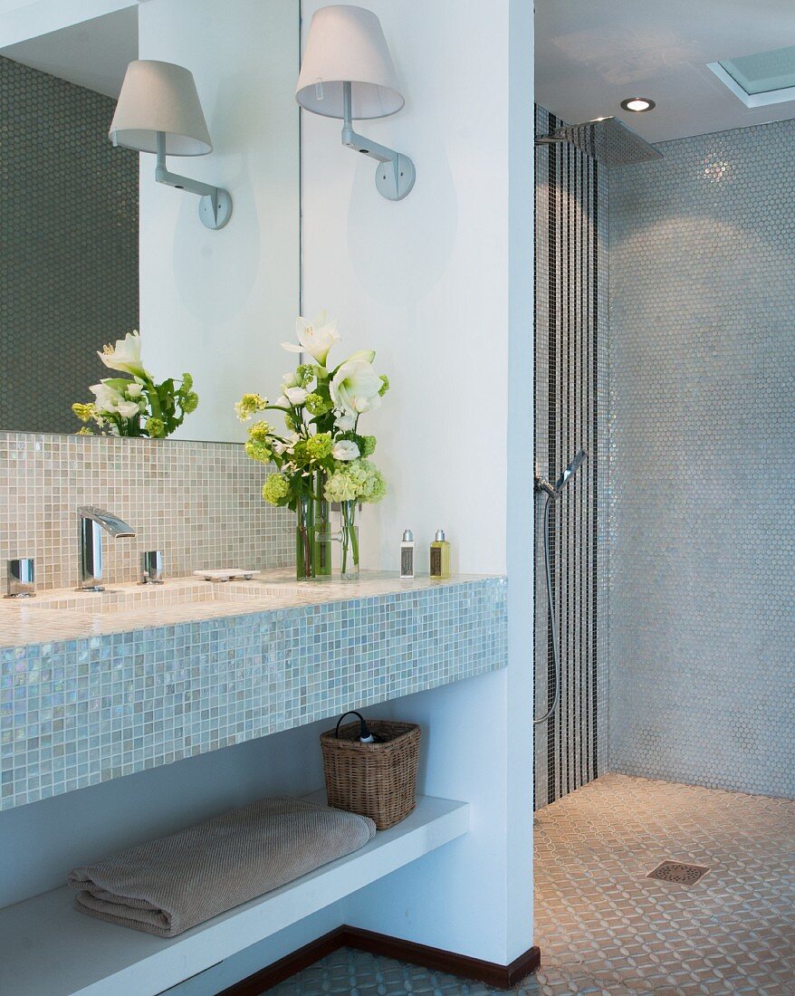 Bad mit Mosaikfliesen, offener Dusche und frischen Blumen