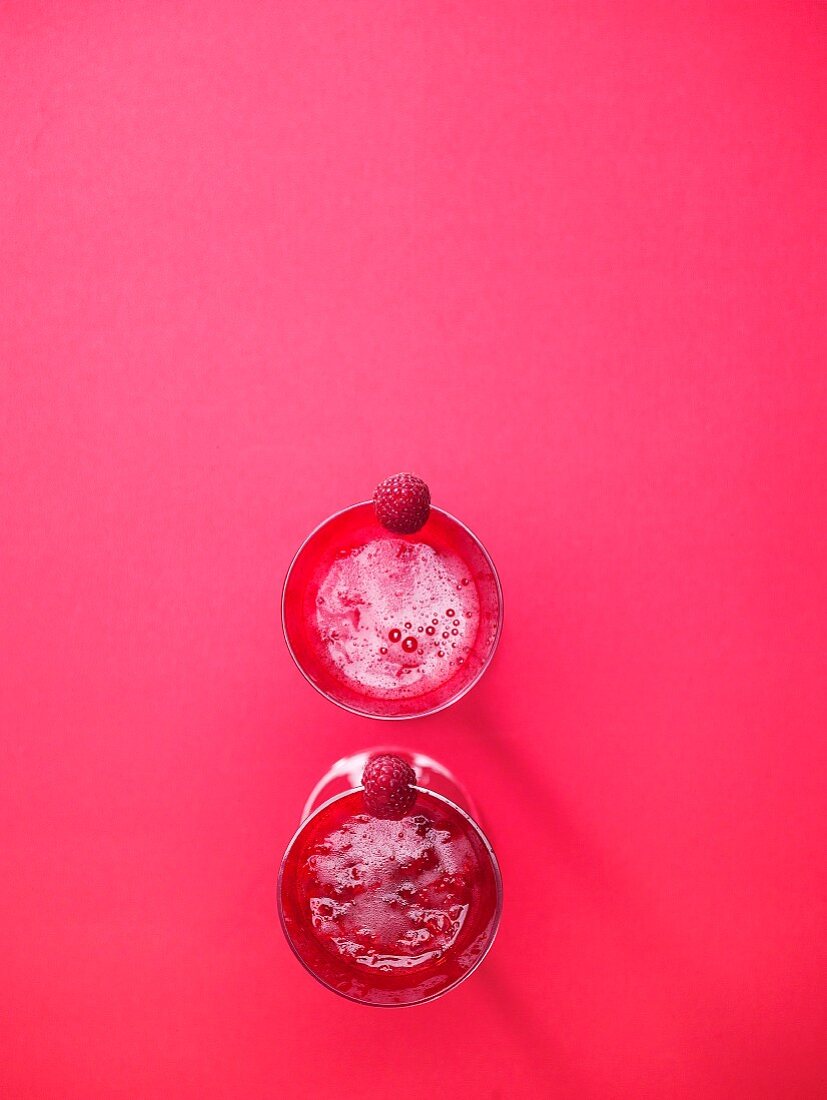 Raspberry smoothies in red cups against a pink background (Valentine's Day)