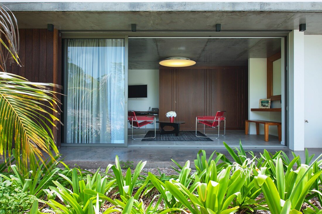 View from garden into living room with open glass wall