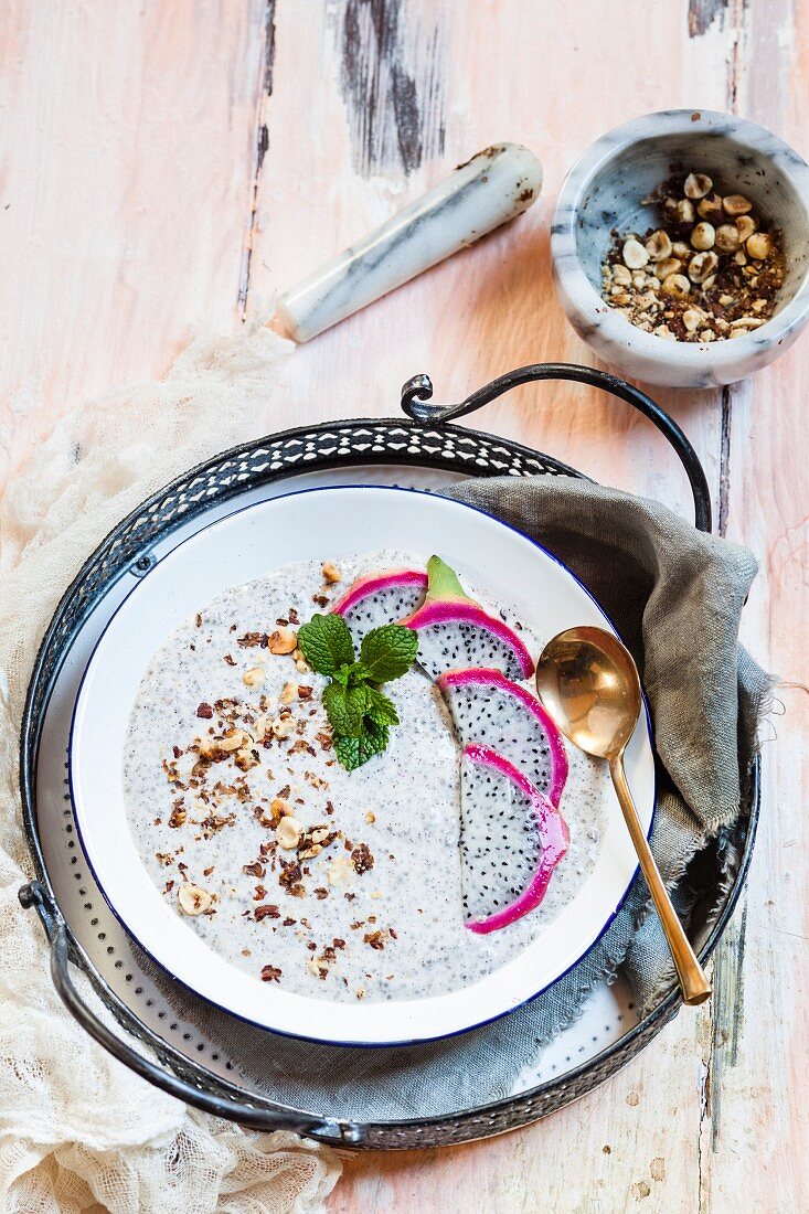 A smoothie bowl with yoghurt, chia seeds, dragon fruit and roasted hazelnuts