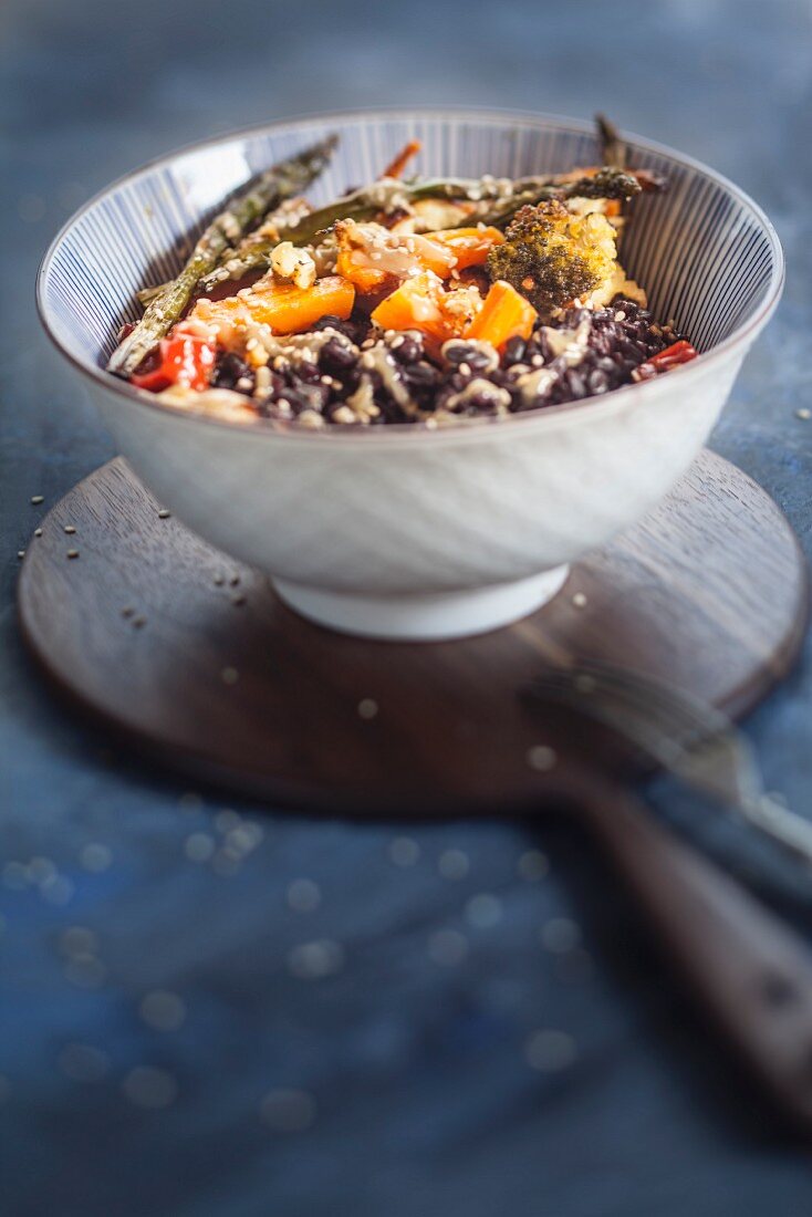 A vegan Buddha bowl with black rice, toasted vegetables and tahini sauce