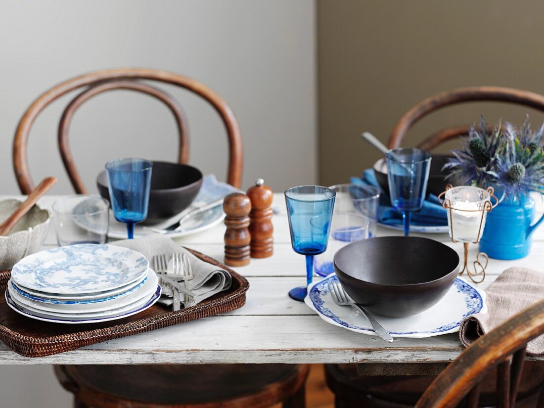 A table laid with blue glasses, blue and white plates and soup bowls