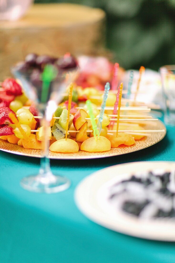 A plate of fruit skewers on a garden table
