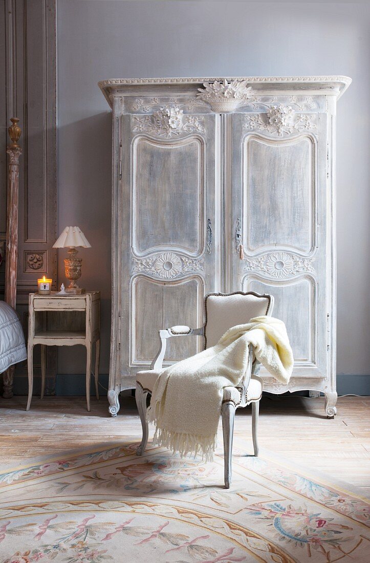 Carved antique wardrobe and blanket on armchair