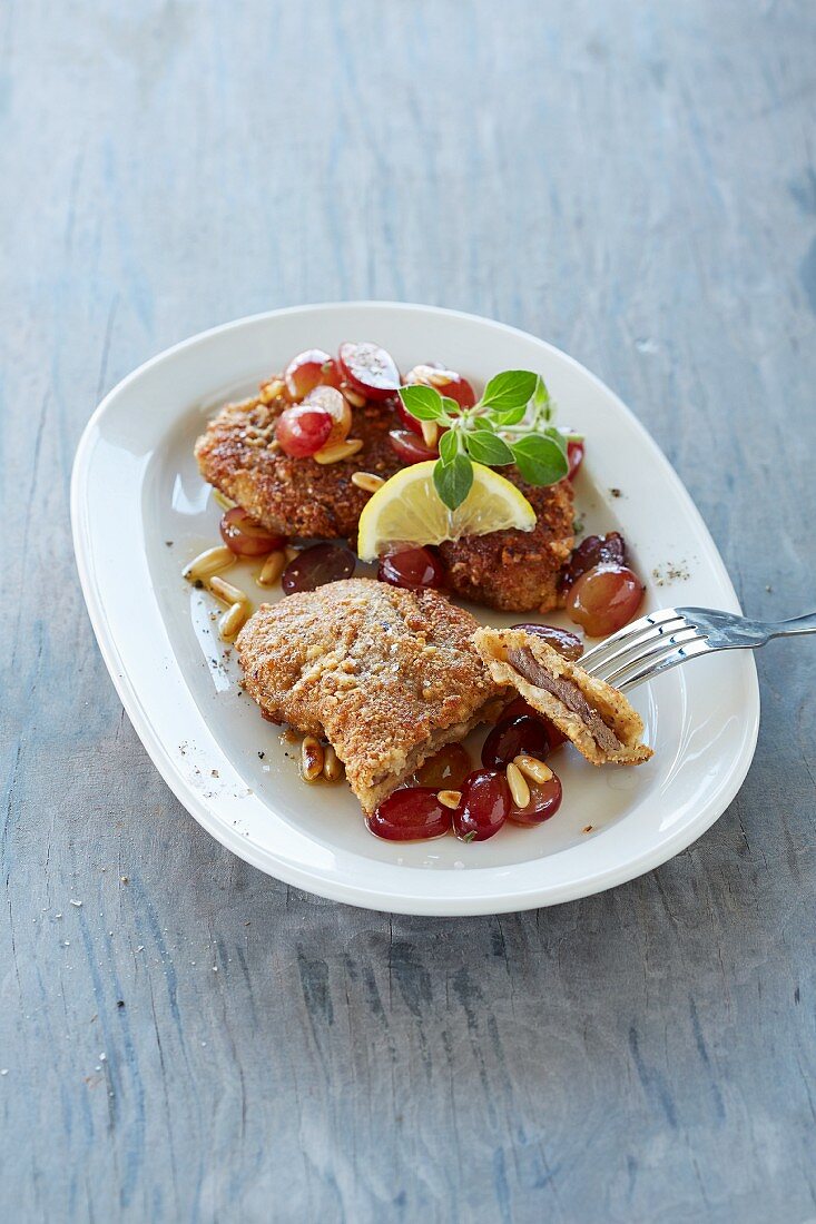 Venison slices in a walnut crumb with grapes and pine nuts