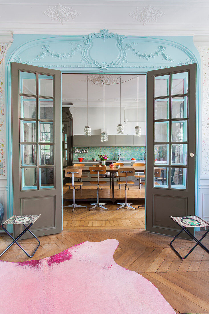 Blick durch farbige Doppeltür mit Sprossenfenstern in die Küche