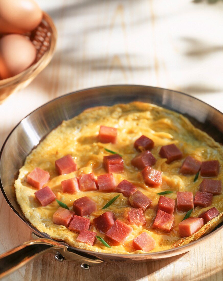 Omelette with ham cubes in a pan