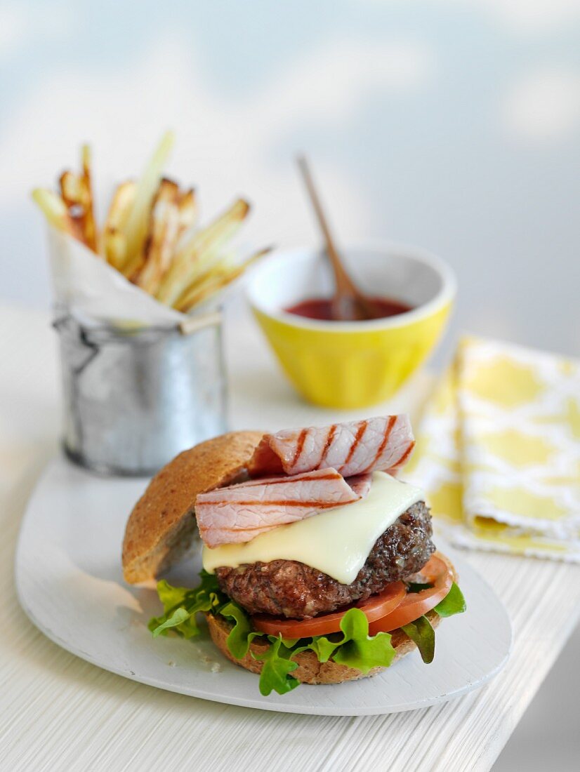 Cheeseburger mit Speck, dazu Pommes und Ketchupsauce