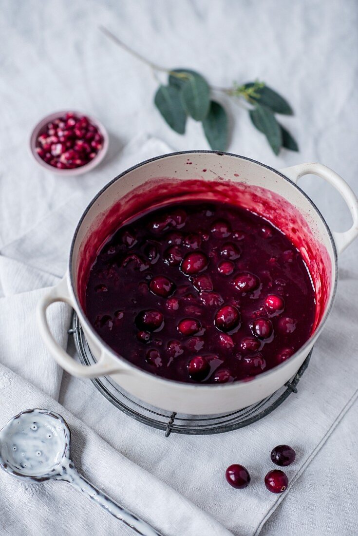 Hot cherries with cranberries and pomegranate seeds in a cooking pot