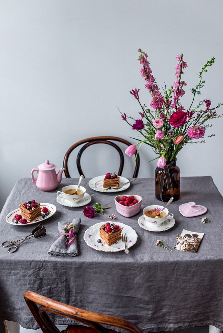 Gedeckter Tisch zum Valentinstag mit Waffeln, Beeren, Tee und Blumenstrauss