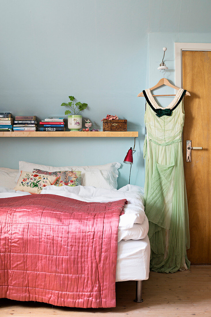 Kleid hängt am Bügel neben dem Bett mit pinker Tagesdecke
