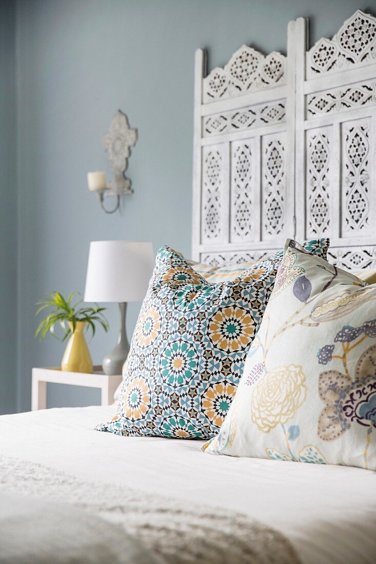 Bett mit Kissen und weißem Betthaupt mit ornamentalem Muster