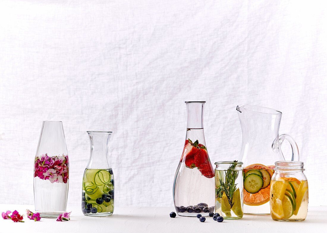 Wasser mit Obst, Gemüse oder Blüten in diversen Karaffen und Gläsern