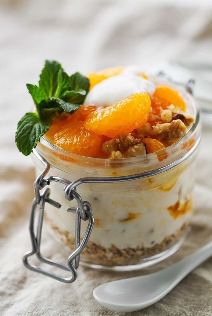 Joghurt mit Mandarinen, Haferflocken, Nüssen, Fruchtsauce und Minze im Weckglas
